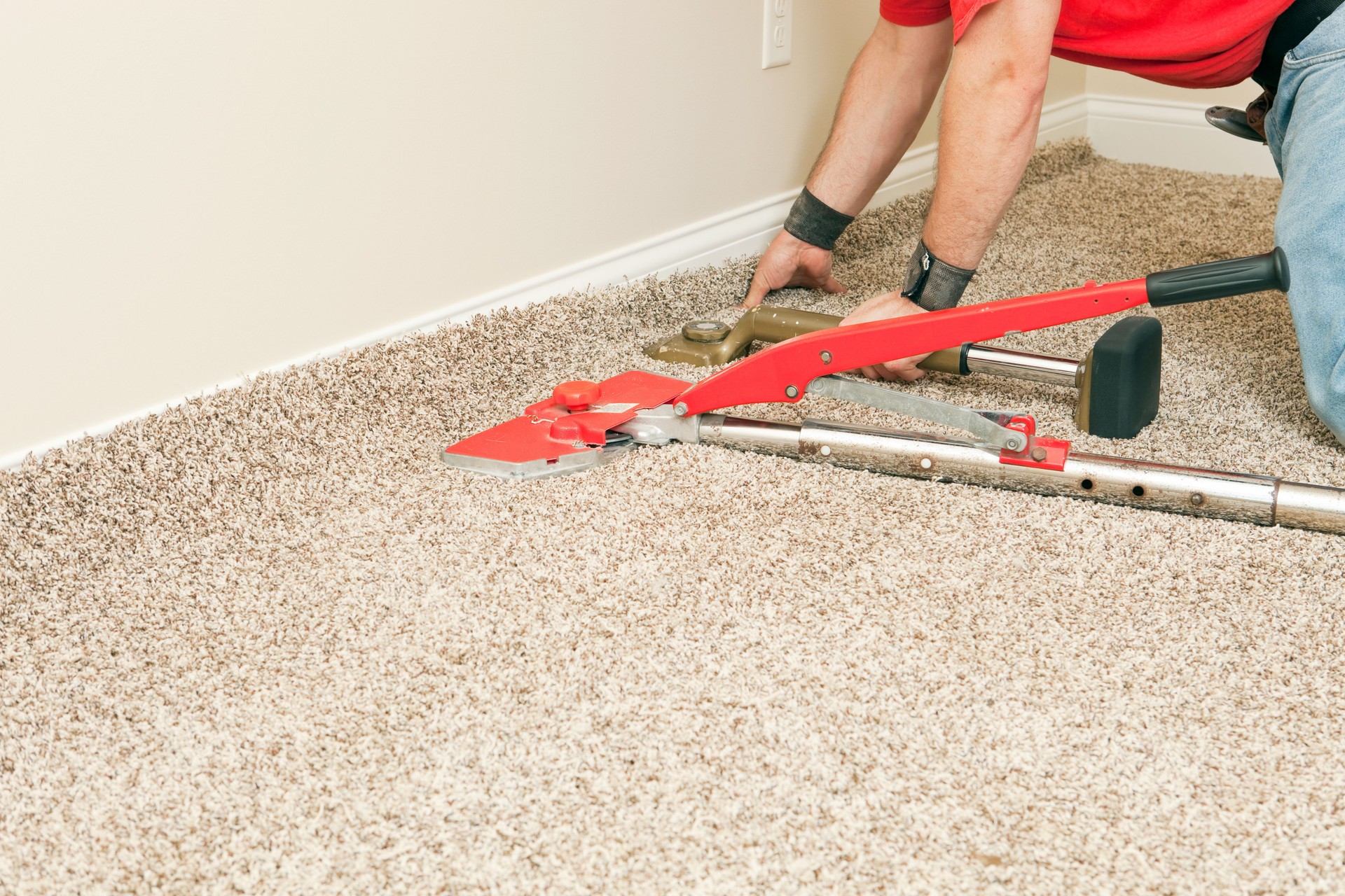 Installer Using Carpet Stretcher on New Bedroom Floor